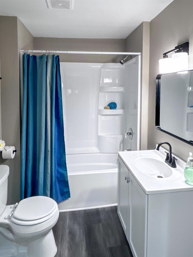 full bathroom with hardwood / wood-style floors, vanity, shower / bath combination with curtain, and toilet