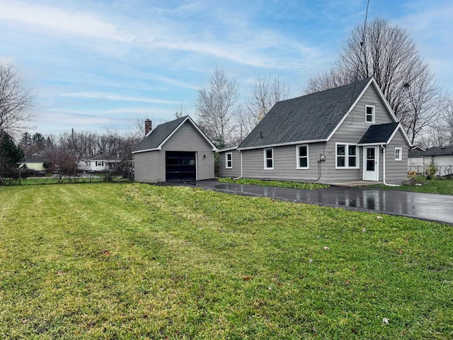 rear view of property featuring a yard, an outbuilding, and a garage