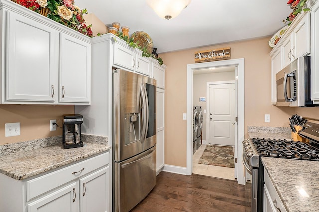 kitchen featuring washer and clothes dryer, dark hardwood / wood-style flooring, white cabinetry, and stainless steel appliances