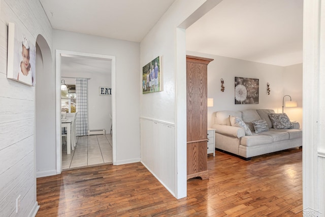 hall with wood-type flooring and baseboard heating