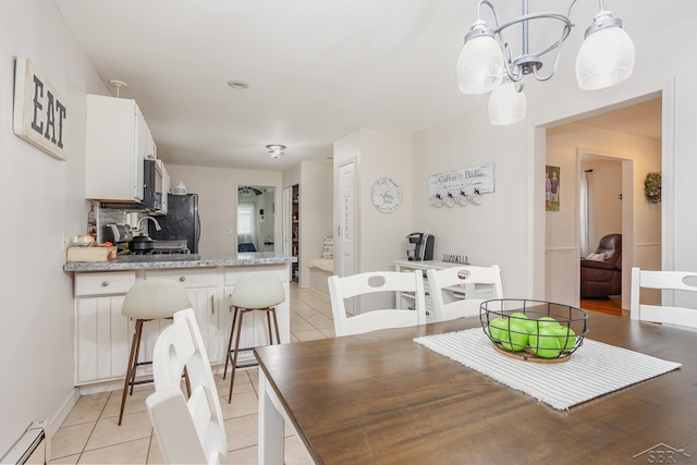 tiled dining space featuring baseboard heating and an inviting chandelier