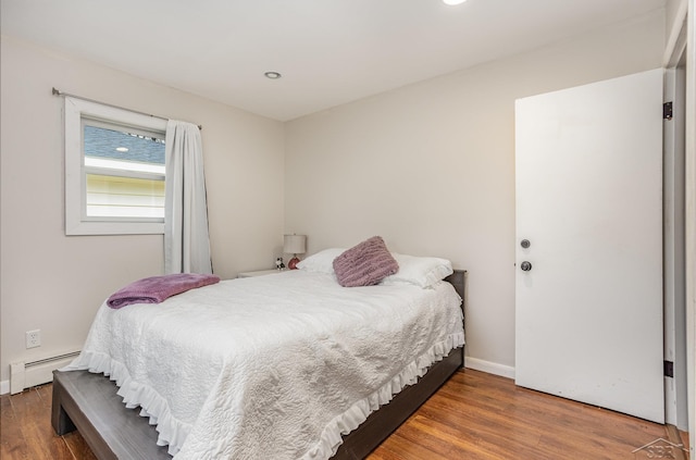 bedroom with dark hardwood / wood-style flooring and a baseboard heating unit