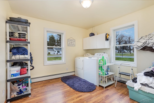 laundry room with cabinets, independent washer and dryer, hardwood / wood-style flooring, and a baseboard heating unit