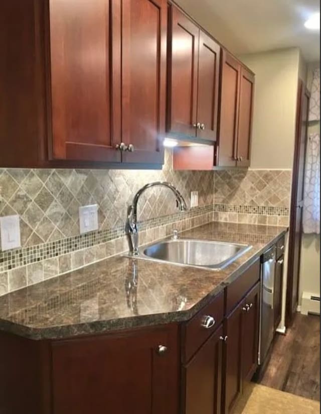 kitchen featuring sink, a baseboard radiator, tasteful backsplash, dark hardwood / wood-style floors, and dark stone counters