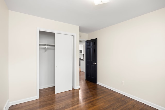 unfurnished bedroom featuring a closet and dark hardwood / wood-style flooring