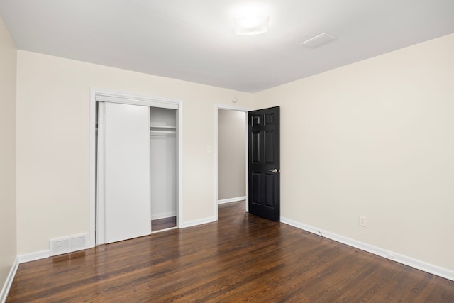 unfurnished bedroom with dark hardwood / wood-style flooring and a closet