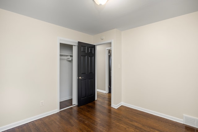 unfurnished bedroom featuring dark wood-type flooring and a closet