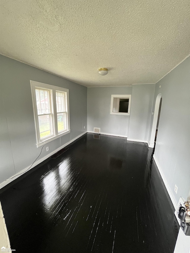 empty room with dark hardwood / wood-style floors and a textured ceiling