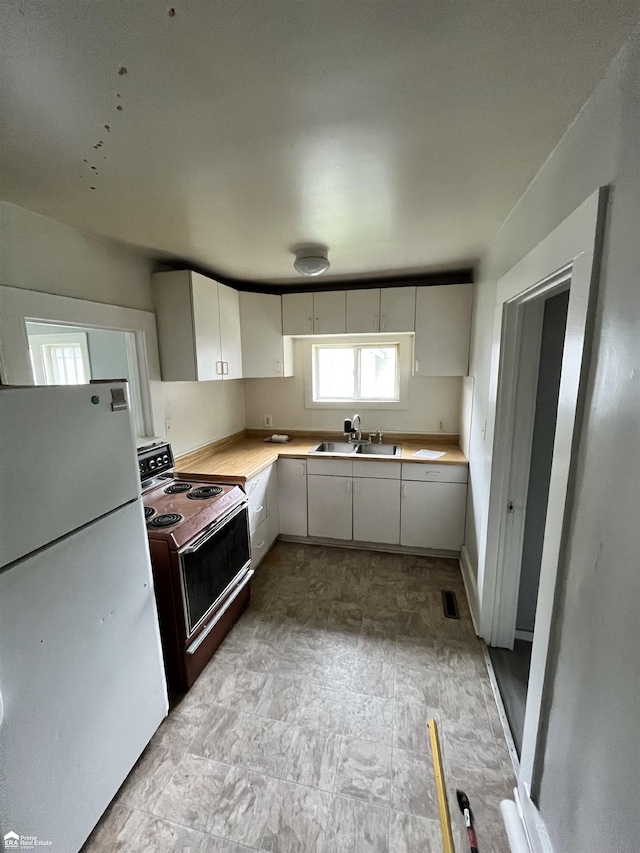 kitchen featuring white cabinets, electric range oven, white fridge, and sink