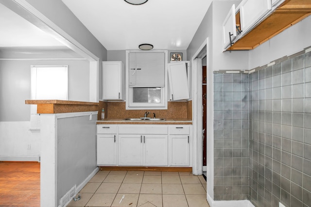 kitchen with white cabinetry, light tile patterned flooring, sink, and tasteful backsplash