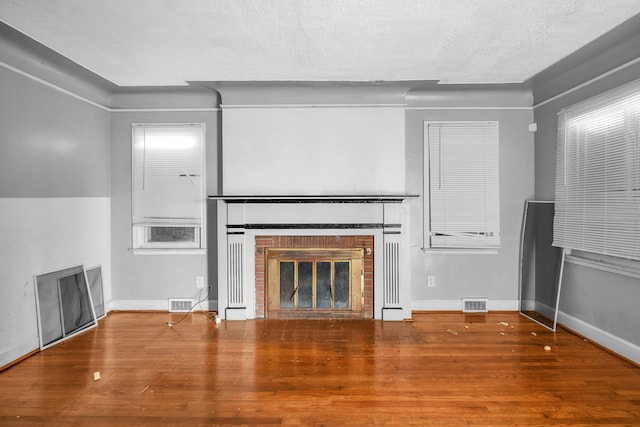 unfurnished living room featuring wood-type flooring, a fireplace, and a textured ceiling