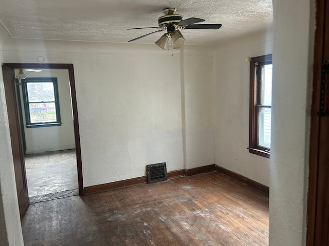 spare room with a textured ceiling, ceiling fan, and dark wood-type flooring