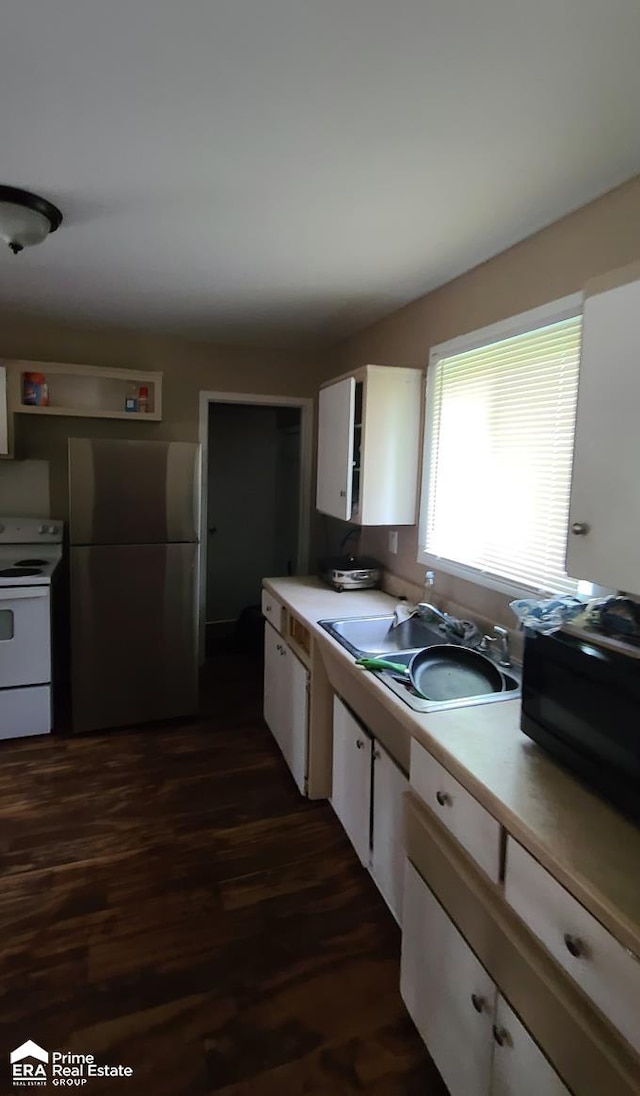 kitchen with electric range, dark hardwood / wood-style floors, white cabinets, and stainless steel refrigerator