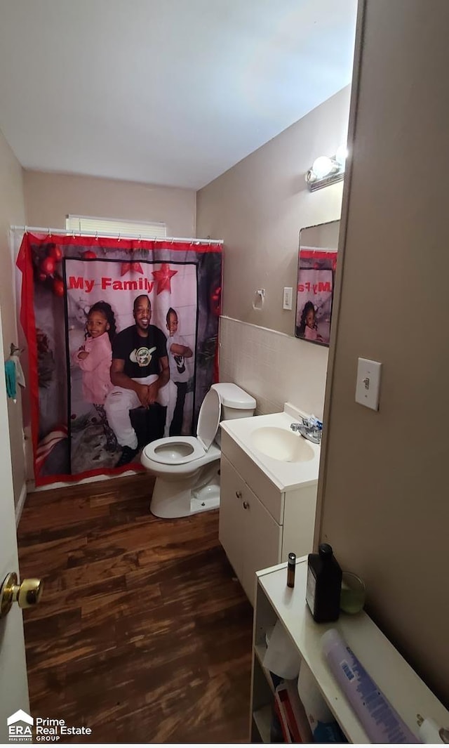 bathroom with wood-type flooring, vanity, toilet, and curtained shower