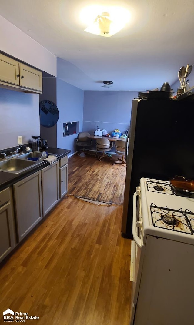 kitchen with gray cabinets, sink, white range with gas stovetop, and dark wood-type flooring