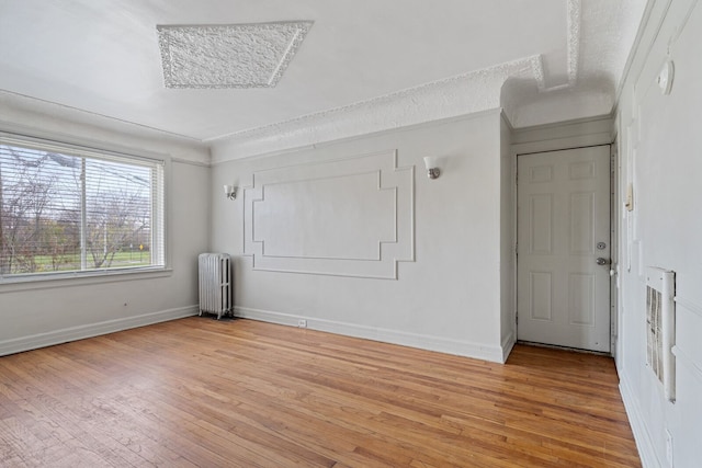 unfurnished room featuring ornamental molding, radiator heating unit, a textured ceiling, and light hardwood / wood-style flooring