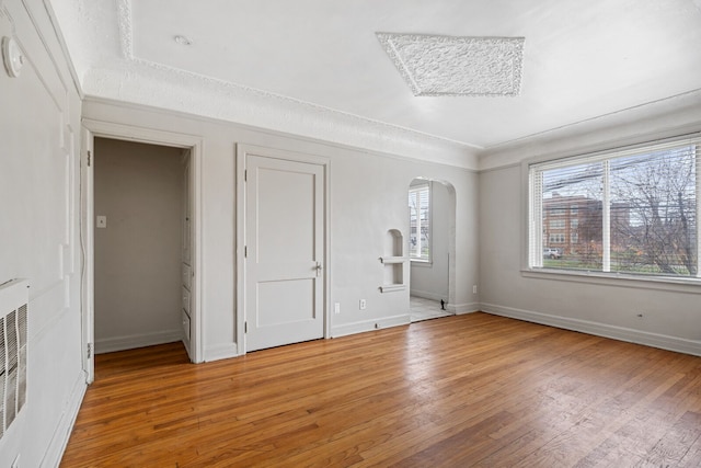 spare room with hardwood / wood-style floors, a textured ceiling, and heating unit