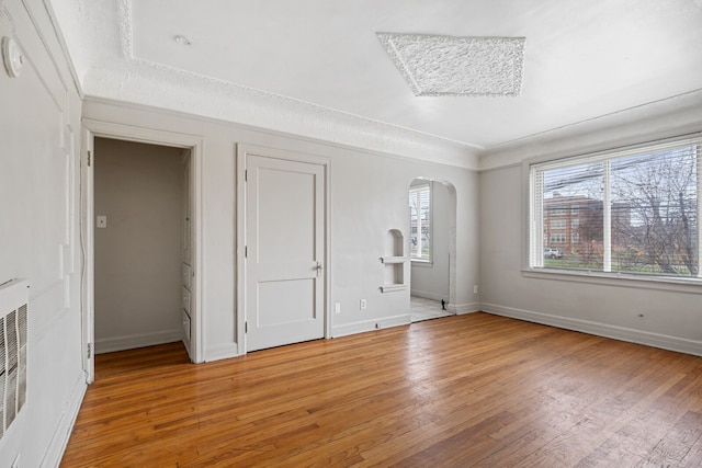 1055 Philip St, Detroit, MI 48215 - unfurnished bedroom featuring arched walkways, light wood finished floors, and baseboards
