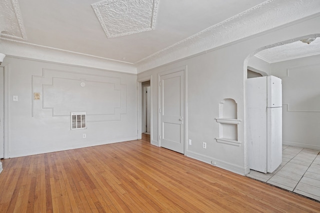 unfurnished room featuring a textured ceiling and light wood-type flooring