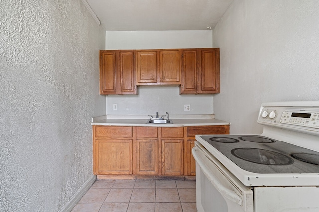 1055 Philip St, Detroit, MI 48215 - kitchen with white range with electric stovetop, light countertops, brown cabinets, a textured wall, and light tile patterned floors