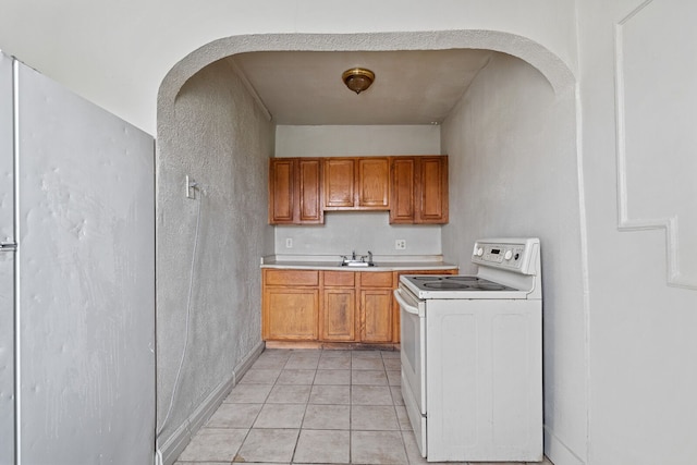 1055 Philip St, Detroit, MI 48215 - kitchen featuring white appliances, light countertops, arched walkways, light tile patterned floors, and brown cabinetry