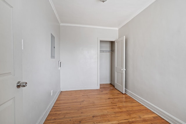 unfurnished bedroom featuring electric panel, light hardwood / wood-style flooring, and ornamental molding