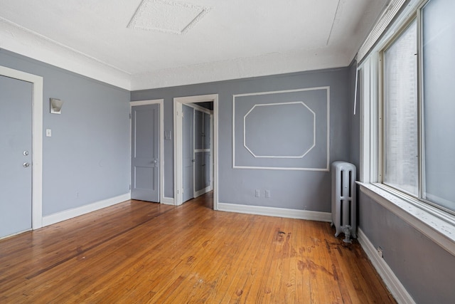 unfurnished bedroom featuring multiple windows, radiator heating unit, a textured ceiling, and light wood-type flooring