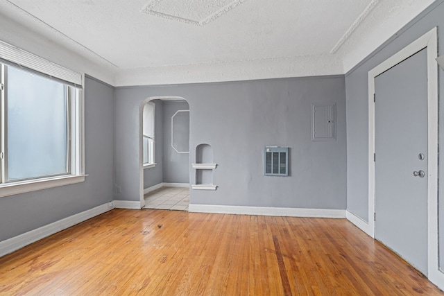 empty room featuring a textured ceiling, light hardwood / wood-style floors, and plenty of natural light