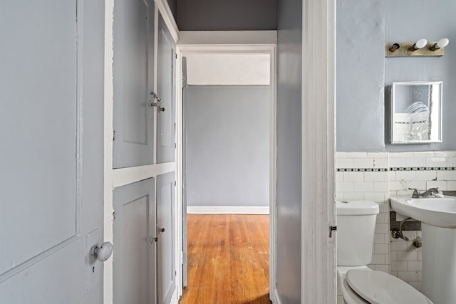 bathroom with toilet, tile walls, and hardwood / wood-style flooring