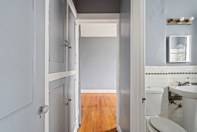 1055 Philip St, Detroit, MI 48215 - half bath featuring tile walls, toilet, a wainscoted wall, and wood finished floors