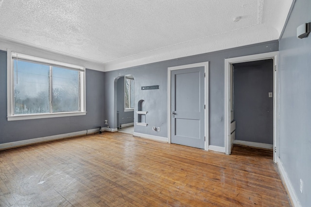 1055 Philip St, Detroit, MI 48215 - empty room with a textured ceiling, arched walkways, wood finished floors, and baseboards
