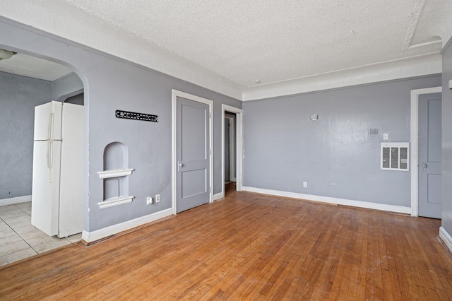 unfurnished living room with light wood-type flooring and a textured ceiling