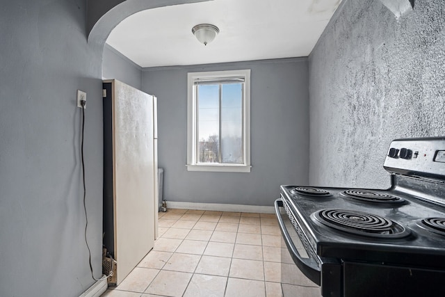 1055 Philip St, Detroit, MI 48215 - kitchen featuring electric range, arched walkways, freestanding refrigerator, and light tile patterned floors