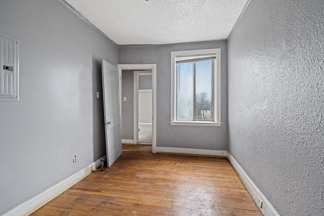 spare room with a textured ceiling and light hardwood / wood-style flooring