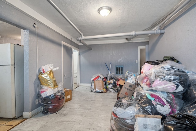 basement featuring a textured ceiling and white refrigerator