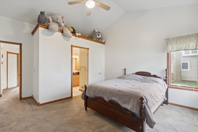 bedroom featuring ceiling fan, vaulted ceiling, light colored carpet, and ensuite bath