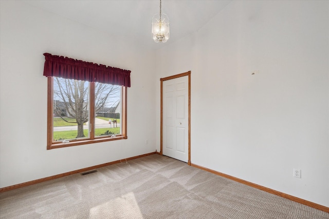 empty room with a notable chandelier and light carpet