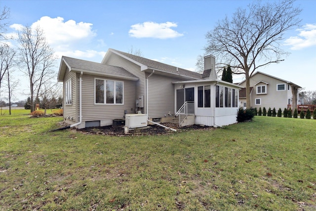 rear view of house featuring a yard and a sunroom