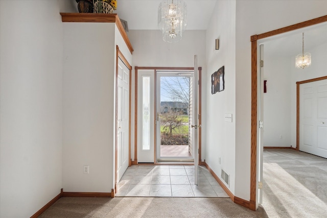 entrance foyer with light colored carpet, plenty of natural light, and a notable chandelier