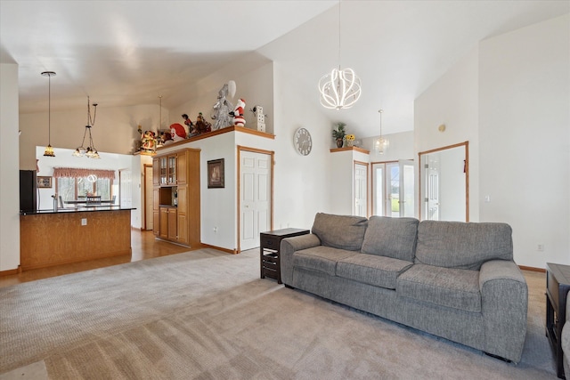 living room with light carpet, high vaulted ceiling, and a chandelier