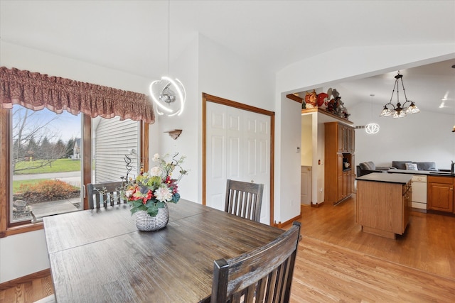 dining area featuring light hardwood / wood-style floors, vaulted ceiling, a notable chandelier, and sink