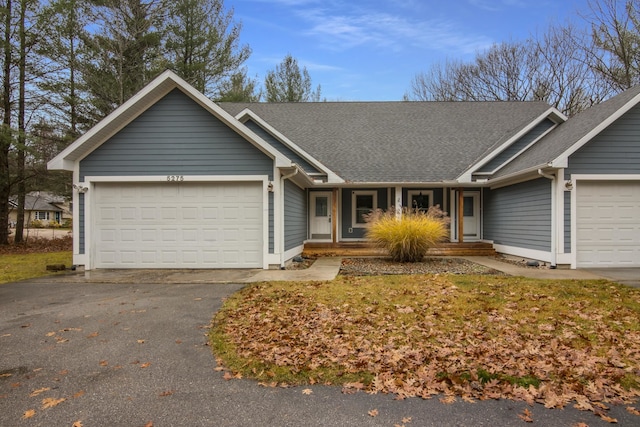5279 Vinton Rd, Williamsburg, MI 49690 - ranch-style house with a garage, a shingled roof, asphalt driveway, and covered porch