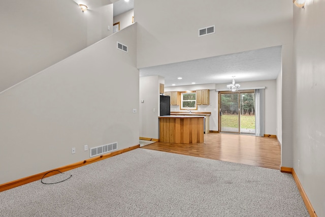 5279 Vinton Rd, Williamsburg, MI 49690 - unfurnished living room with light colored carpet, baseboards, and a chandelier
