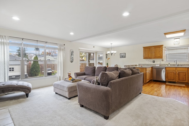 living room with light hardwood / wood-style floors, an inviting chandelier, and sink