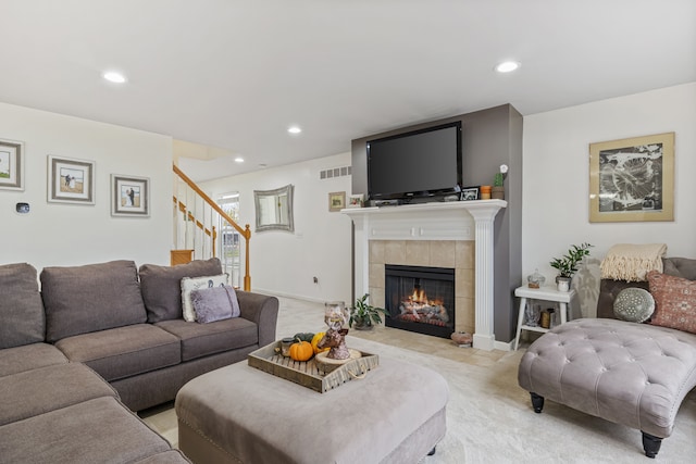 living room featuring a tile fireplace and light colored carpet