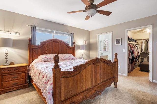 carpeted bedroom with a walk in closet, a closet, ensuite bath, and ceiling fan