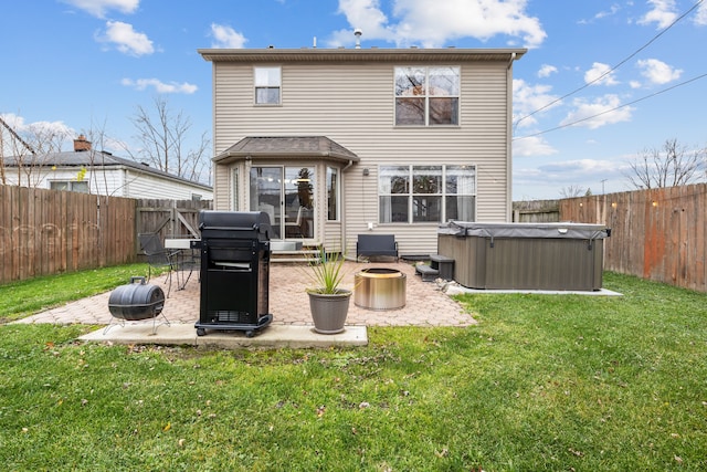 back of property with a patio, a hot tub, an outdoor fire pit, and a lawn