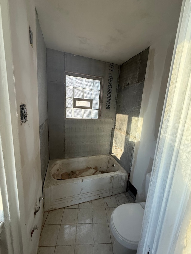 bathroom featuring tile patterned floors, a washtub, and toilet