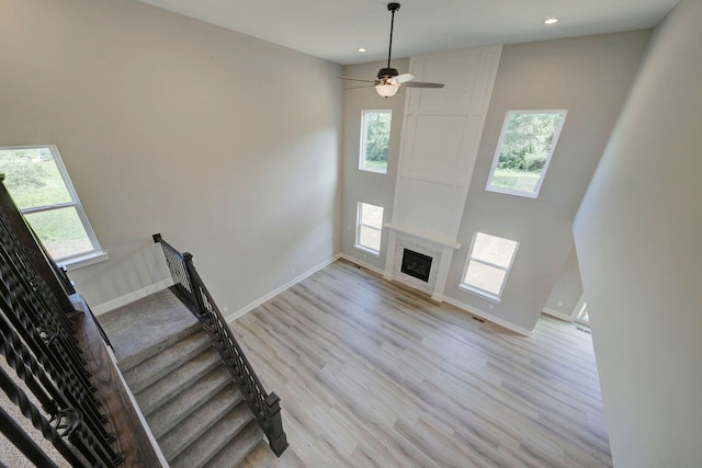 interior space with a fireplace, ceiling fan, hardwood / wood-style floors, and a high ceiling