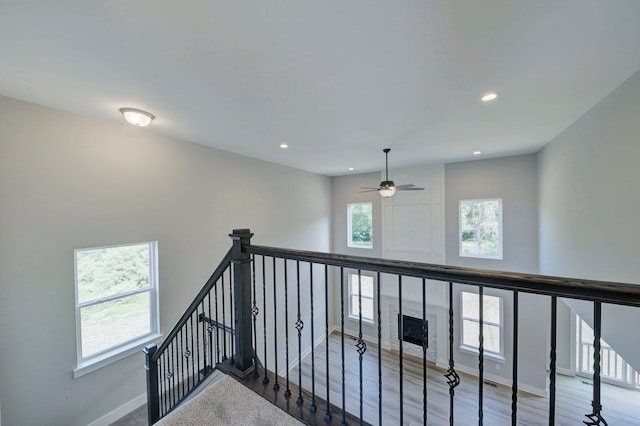 stairs with a wealth of natural light, ceiling fan, and wood-type flooring